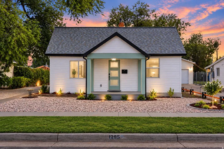 White siding exterior with a dark shingle roof, complemented by a covered entry with mint-colored trim