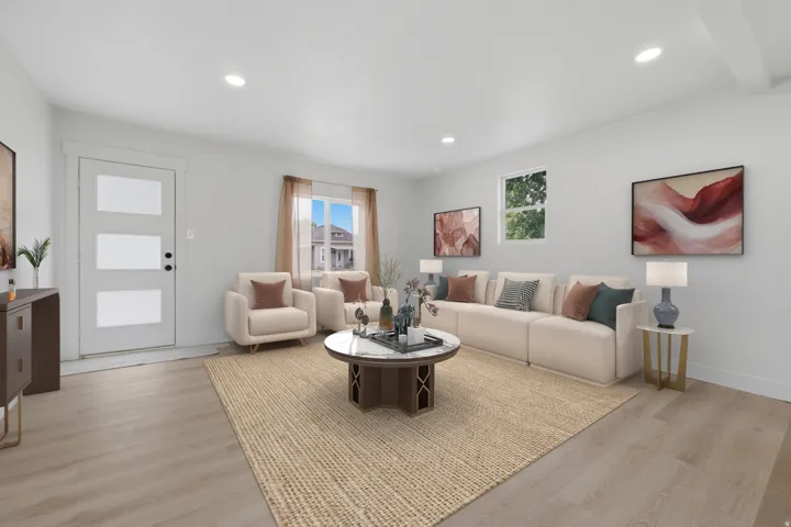 Spacious living area featuring light wood-finish flooring, recessed lighting, and ample natural light from multiple windows