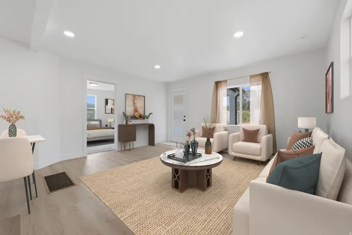 Spacious living area featuring light wood-finish flooring, recessed lighting, and bright white walls
