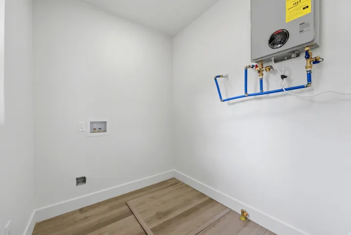 Utility area featuring a wall-mounted tankless water heater, PEX plumbing, and a washing machine hookup