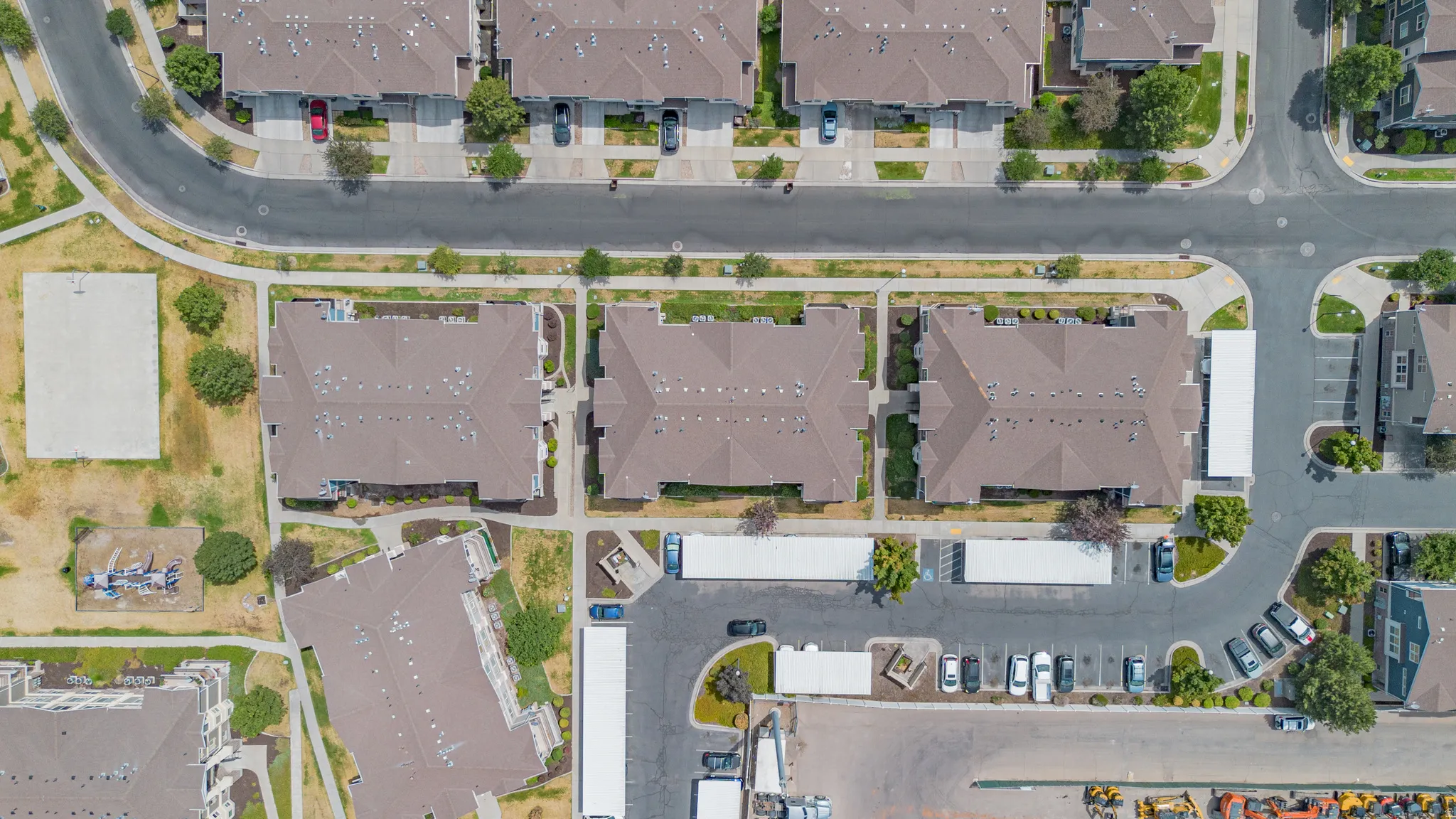 Aerial perspective showcasing multiple residential buildings with brown shingle roofs, surrounded by manicured green spaces
