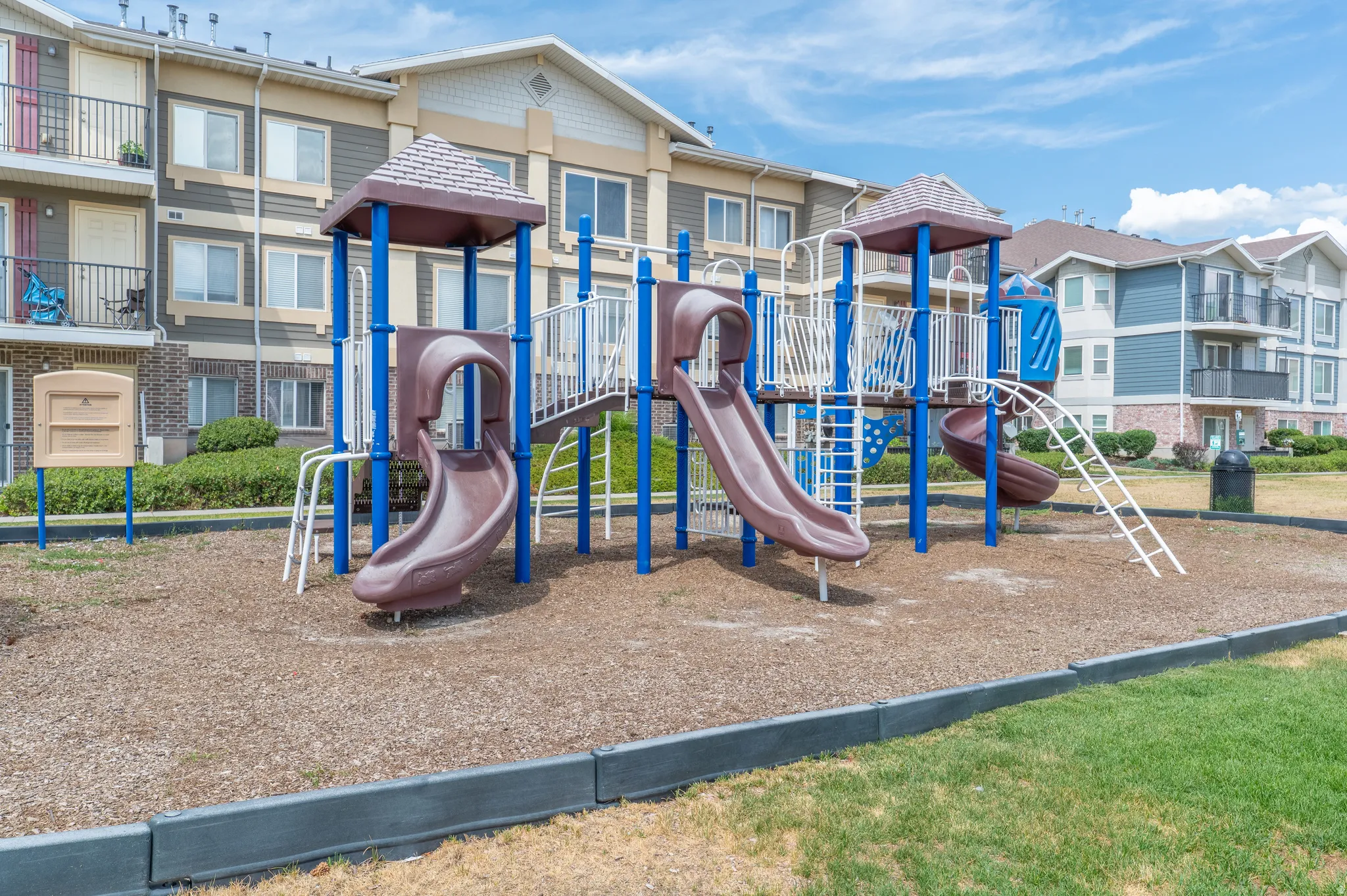 Playground area featuring multiple slides, climbing structures, and protective ground covering