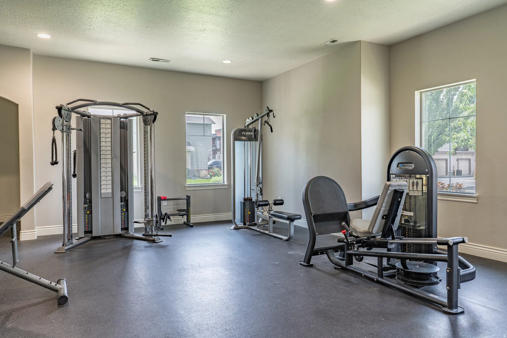 Dedicated fitness center featuring robust exercise equipment, resilient rubber flooring, multiple windows, recessed lighting, and neutral wall tones