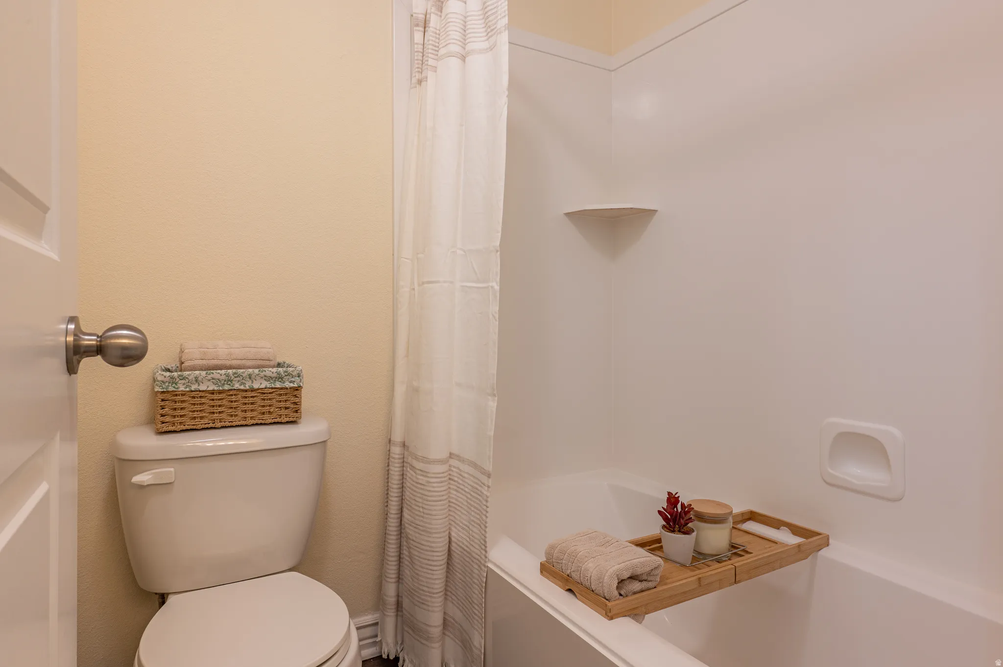 Bathroom featuring a white bathtub, integrated shower, and a white toilet