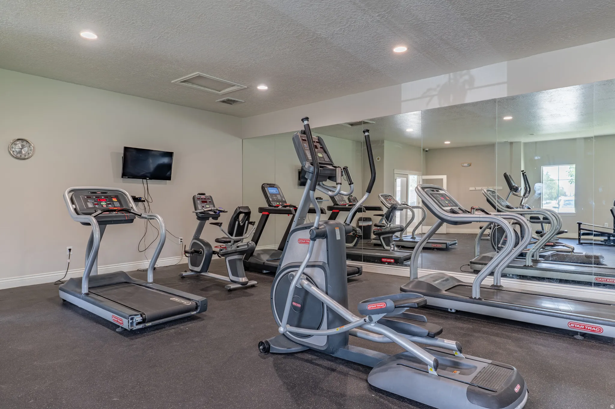 Fitness center featuring multiple cardio machines, full-wall mirrors, recessed lighting, and rubber flooring