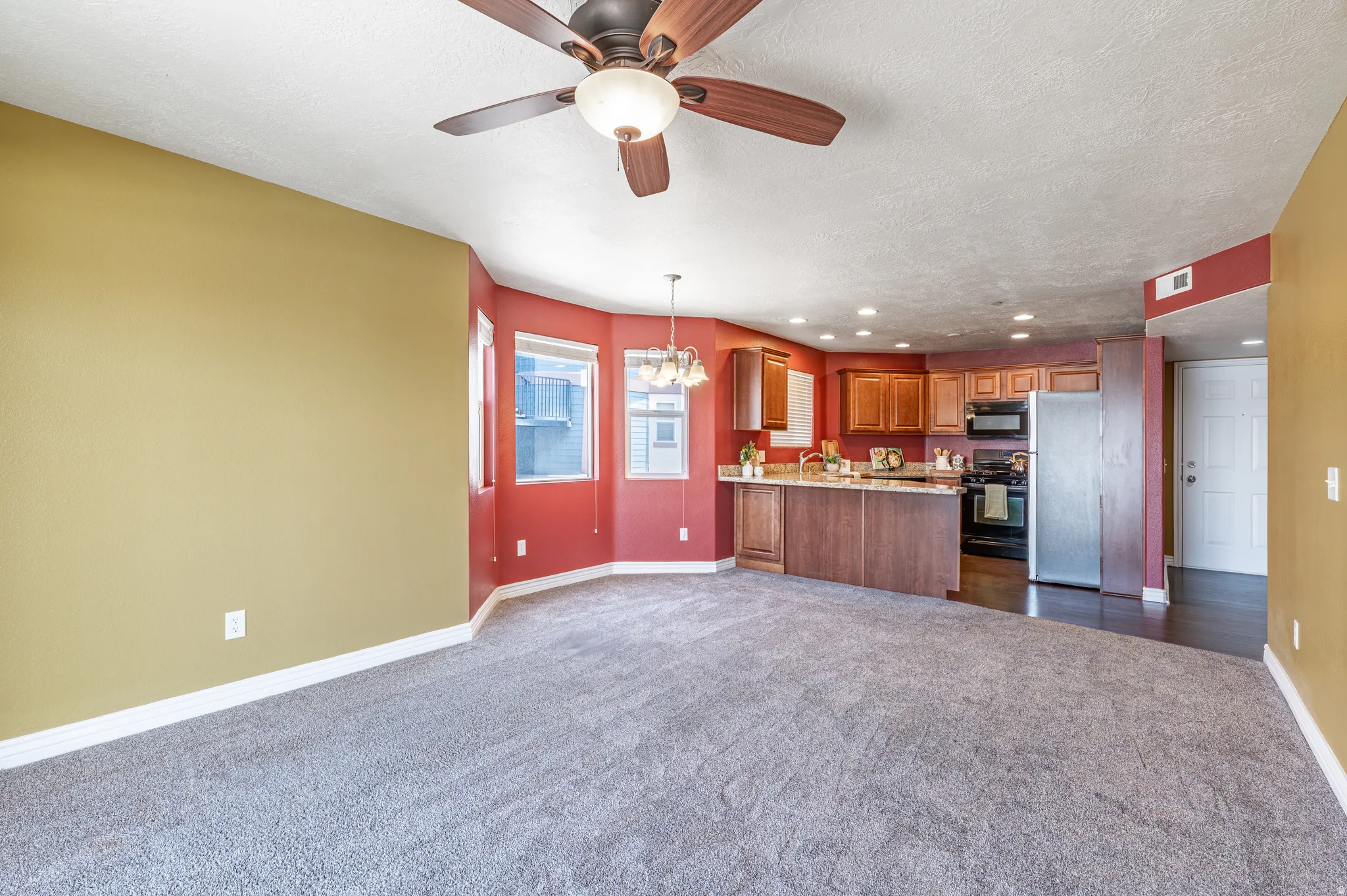 Open concept living area featuring a kitchen with wood cabinetry, stainless steel refrigerator, and built-in microwave