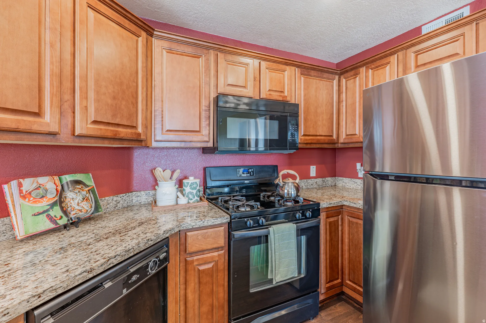 Kitchen featuring light wood cabinetry, stone-finish countertops, and red painted walls