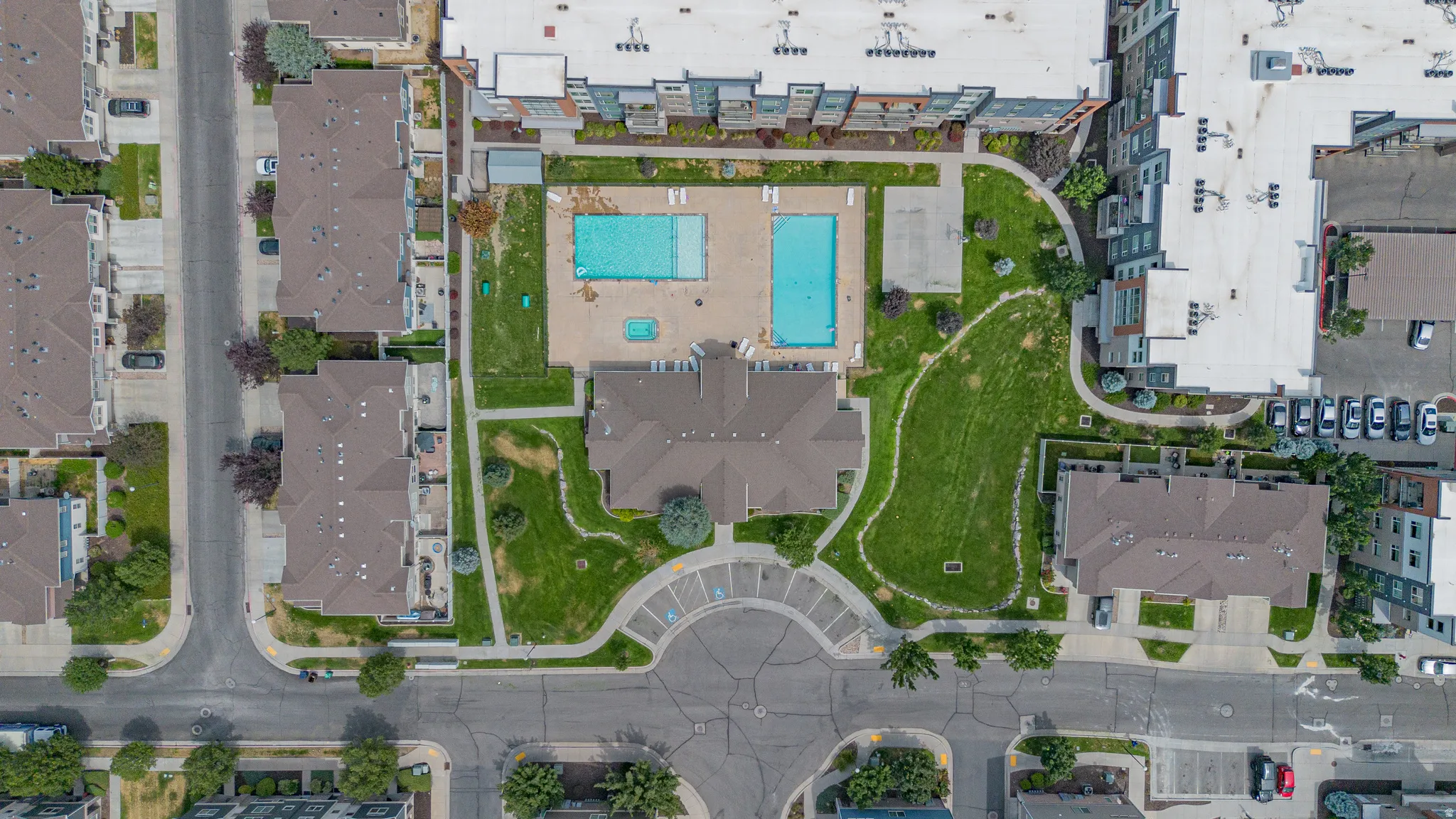 Community amenity area featuring two swimming pools, a clubhouse, and expansive green spaces with walking paths