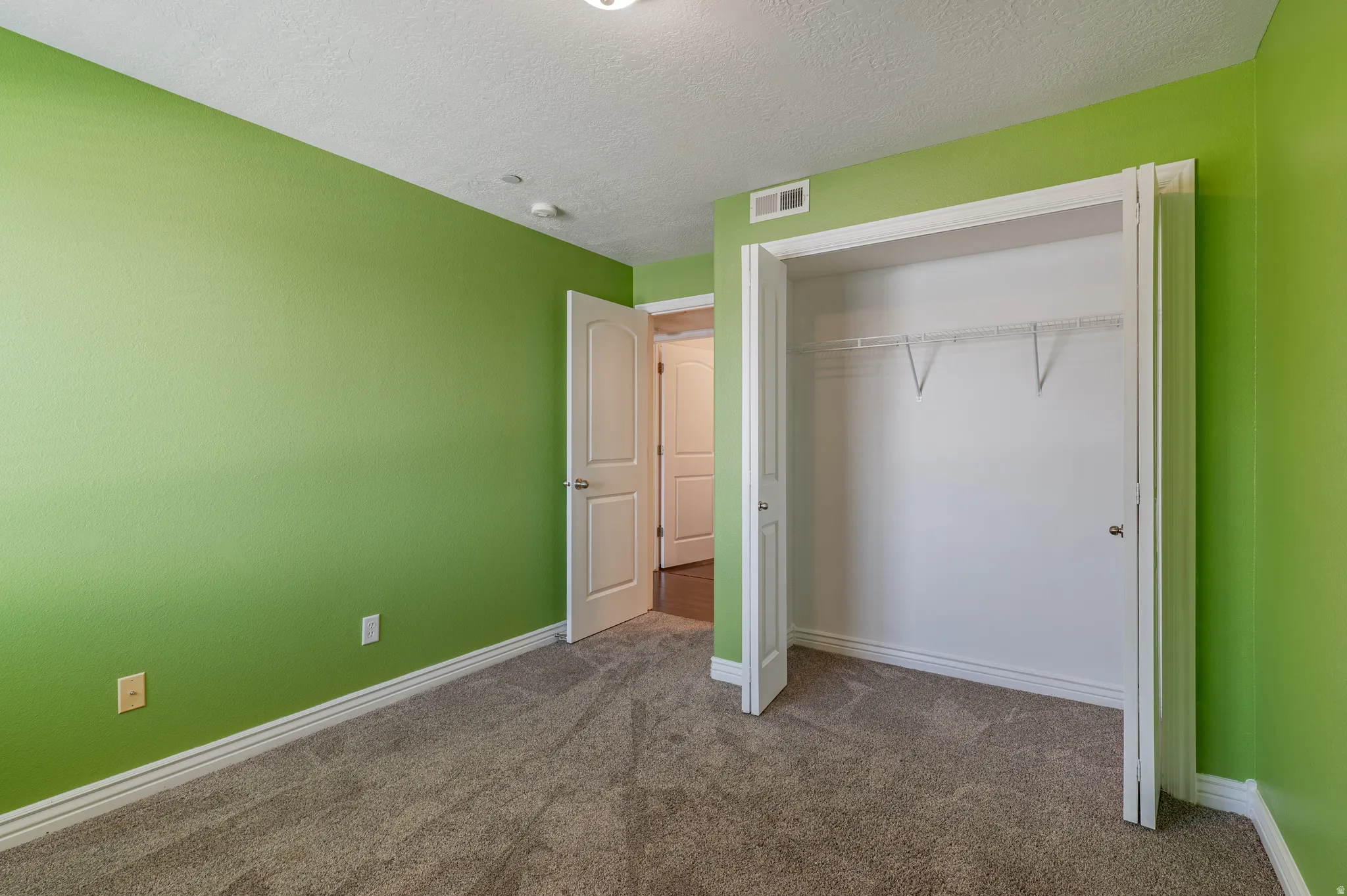 Bedroom featuring vibrant green walls and neutral gray carpeting