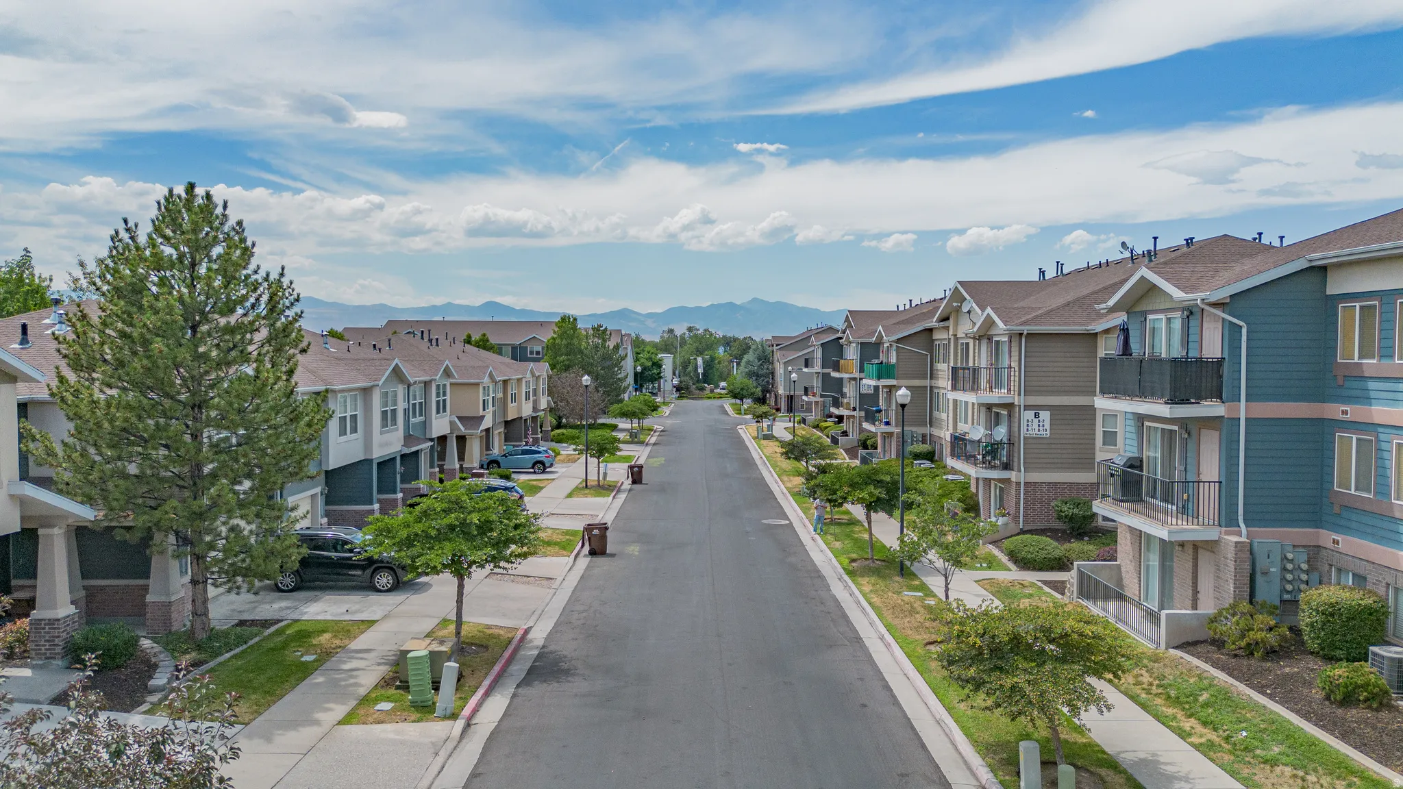 Residential street lined with multi-story townhomes and apartment buildings