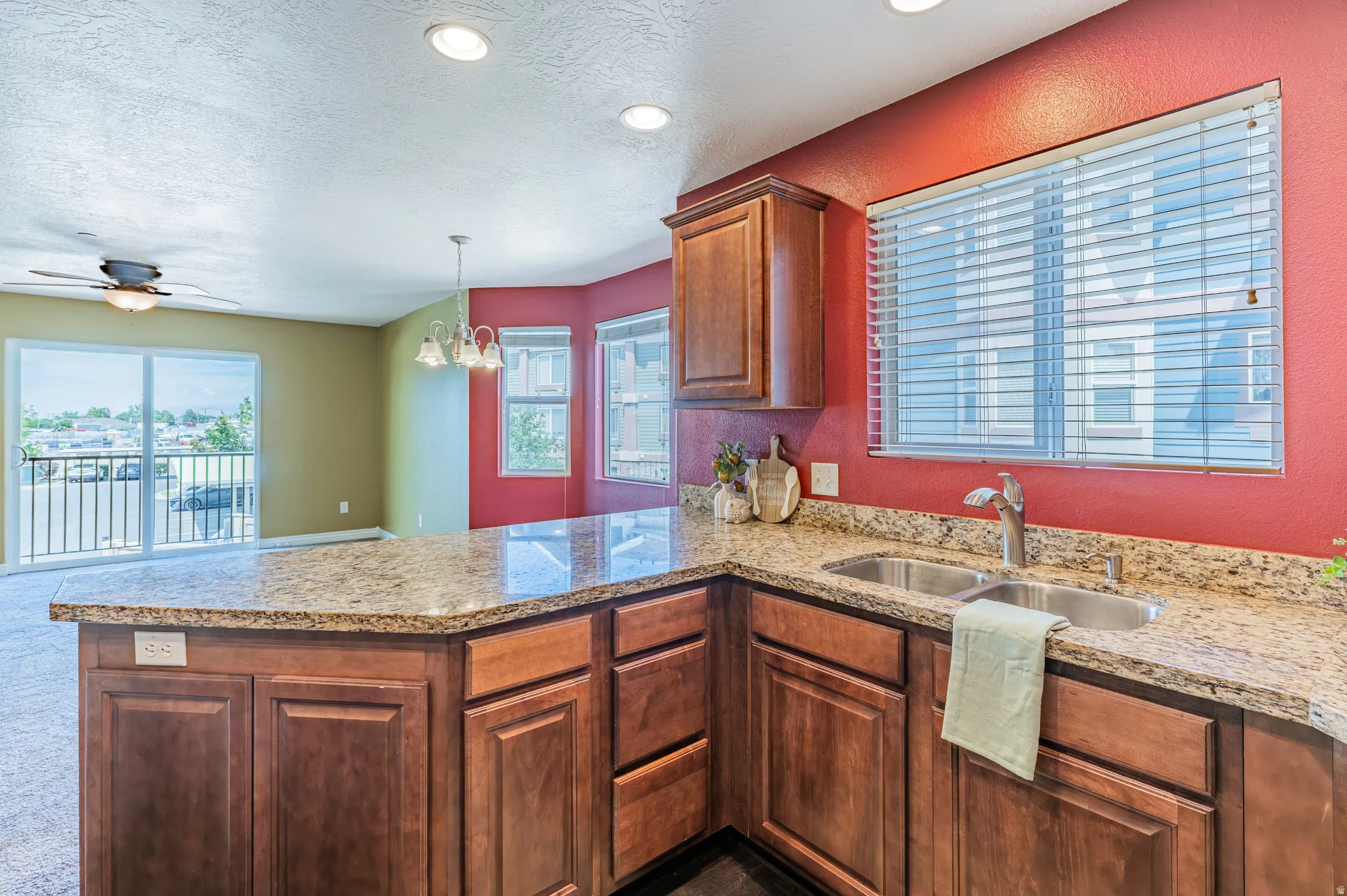 Kitchen island featuring a double basin stainless steel sink, granite countertops, and wood cabinetry
