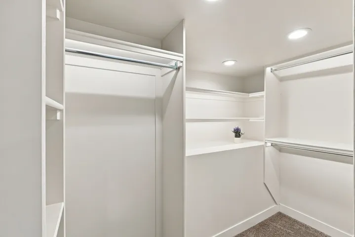 Walk-in closet featuring recessed lighting, multiple hanging rods, built-in shelving, and carpet flooring