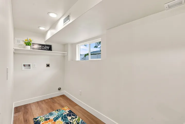 Utility area featuring wood-finish flooring, white walls, and a single window