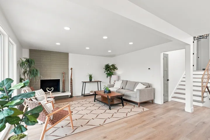 Spacious living area featuring light wood-finish flooring, recessed lighting, and large windows