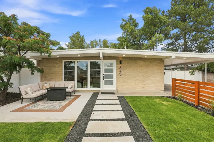 Mid-century modern residence featuring a light brick facade, a covered carport, and a white flat roofline