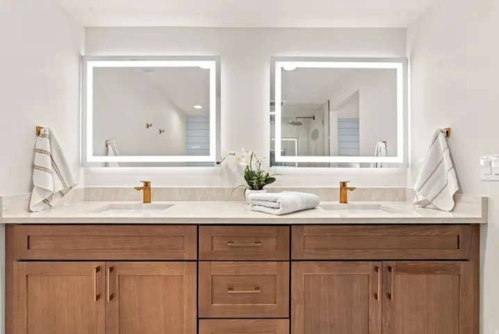 Dual vanity featuring wood-finish cabinetry, integrated sinks, and light-toned countertops