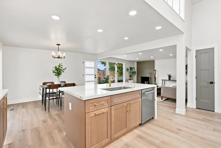 Kitchen island with light wood-finish cabinetry, white countertop, and integrated stainless steel dishwasher