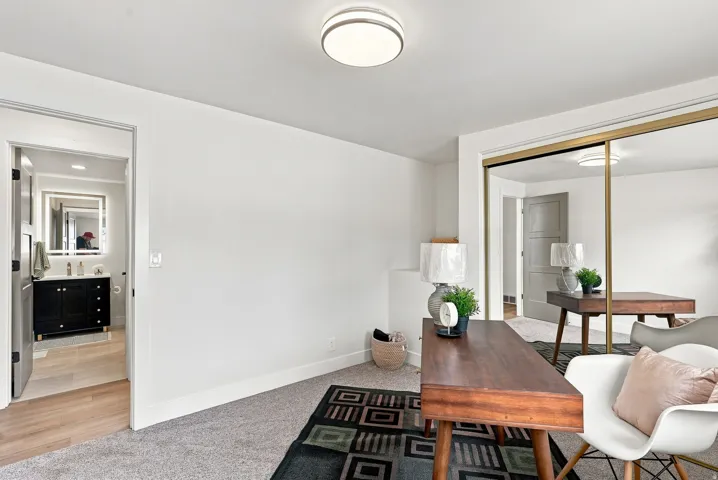 Bedroom featuring light gray carpeting, a built-in closet with gold-framed mirrored doors, and a flush-mount ceiling light fixture