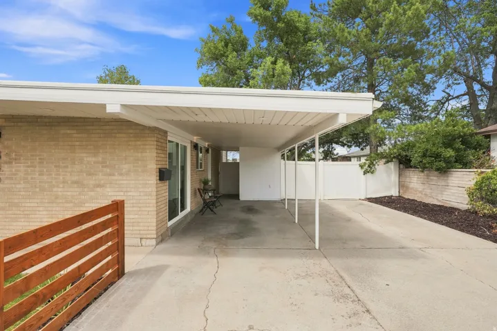 Carport entry featuring a brick exterior and a white lattice fence