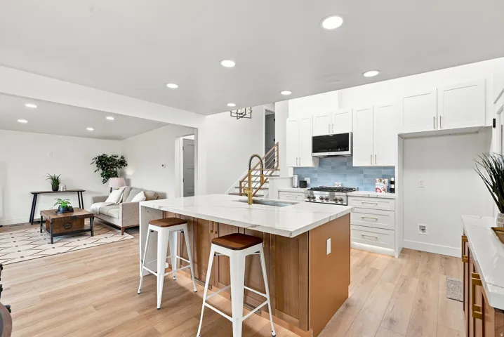 Kitchen island with a light-toned countertop and wood-finish cabinetry, featuring a gooseneck faucet and integrated sink
