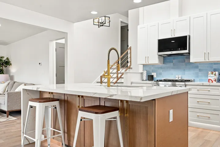 Kitchen island featuring a waterfall countertop with veining, a gooseneck faucet, and wood-finish cabinetry