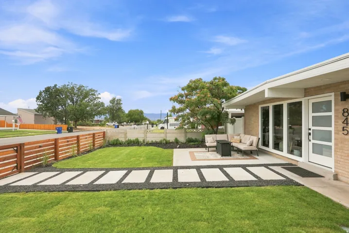 Front facade featuring light brick siding, a white entry door with frosted glass panels, and a concrete patio
