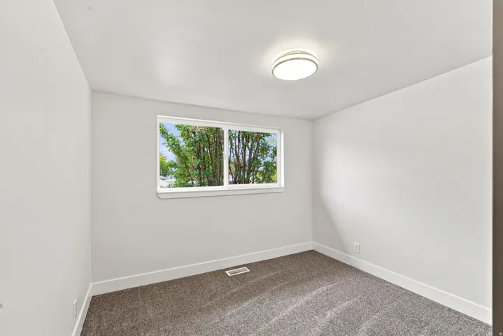 Neutral-toned walls, gray carpet, and a large window with white trim