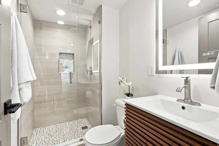 Modern bathroom featuring a glass-enclosed shower with pebble-tile flooring and a recessed niche