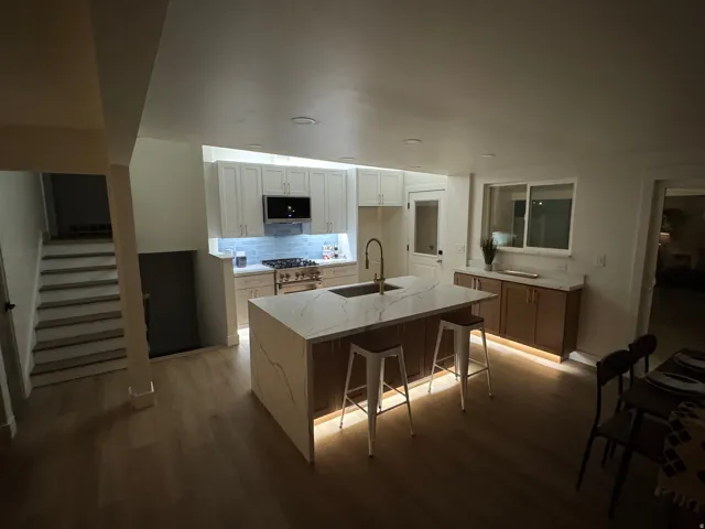 Gourmet kitchen featuring a waterfall island with integrated seating, white shaker cabinetry, a subway tile backsplash, and stainless steel appliances