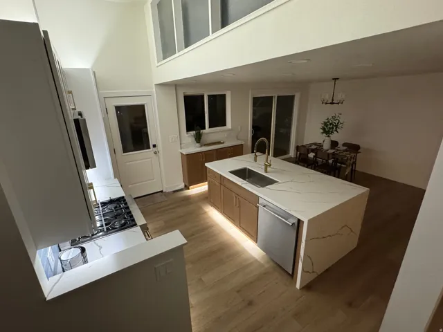Modern kitchen featuring a waterfall island with an undermount sink and built-in dishwasher