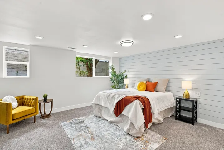 Spacious room featuring light gray carpeting, a decorative shiplap accent wall, recessed lighting, and multiple windows