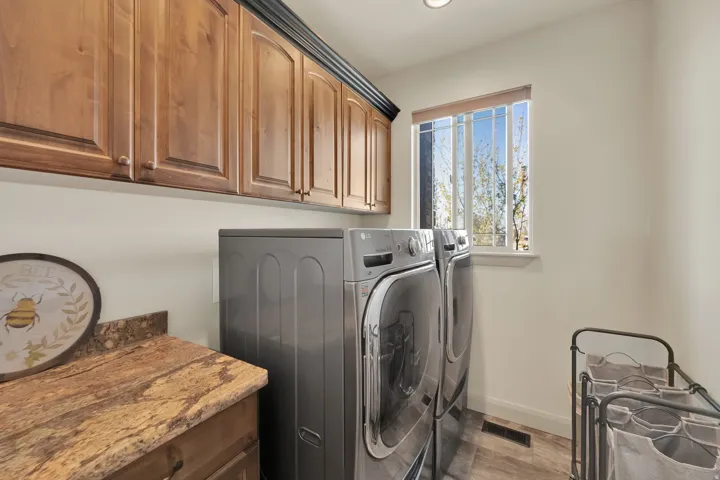 Laundry room featuring wood cabinetry with crown molding, a built-in countertop with stone finish, and wood-finish flooring