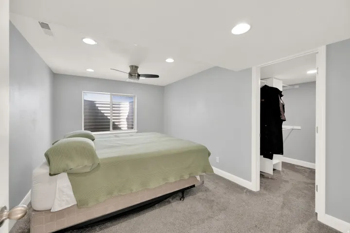 Carpeted bedroom featuring recessed lighting, a ceiling fan, a window with horizontal blinds, and an open closet with built-in shelving