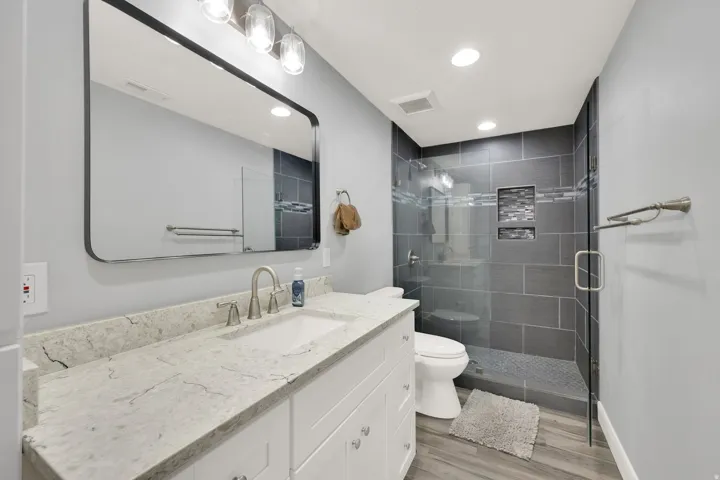 Modern bathroom featuring a contemporary vanity with a stone-finish countertop and integrated sink