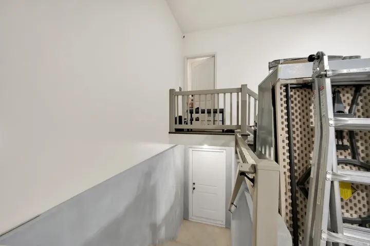Multi-level interior space featuring a light gray railing on the upper platform and white doors on both levels