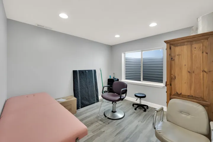 Spacious room featuring light gray walls, recessed ceiling lighting, a large window with a window well, and wood-finish flooring