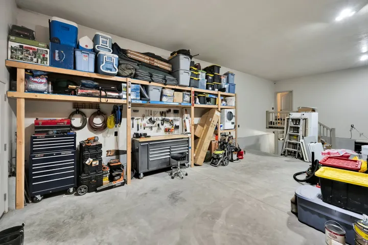 Spacious garage featuring high ceilings with recessed lighting, concrete flooring, and extensive built-in wooden shelving for ample storage