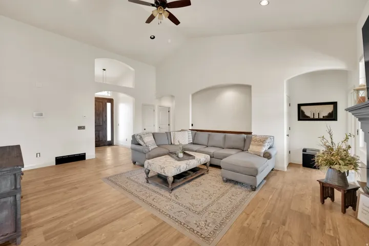 Spacious living area featuring light wood-finish flooring, vaulted ceilings, and recessed lighting