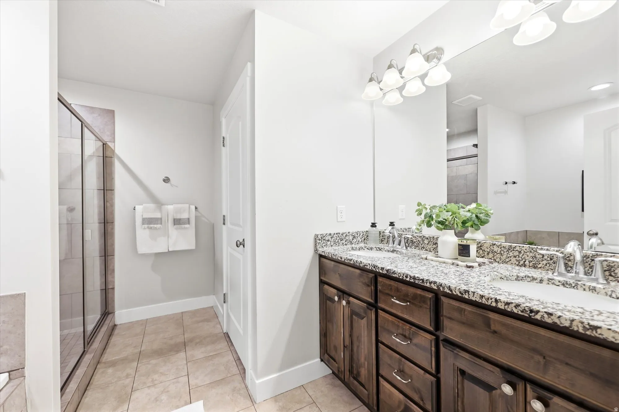 Dual vanity in master bedroom with dark wood cabinetry and granite countertops, featuring two undermount sinks and brushed nickel fixtures