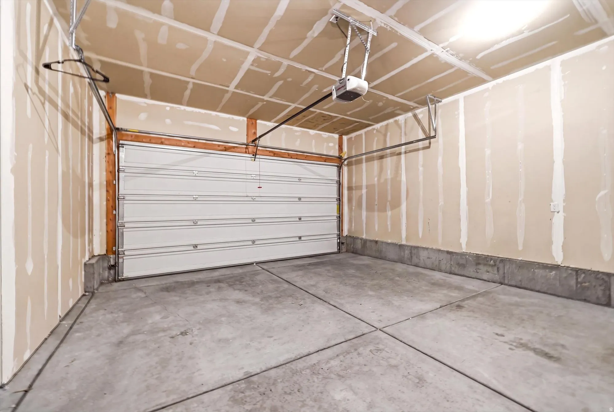 Attached garage featuring a concrete floor, automatic door opener, and unfinished drywall walls
