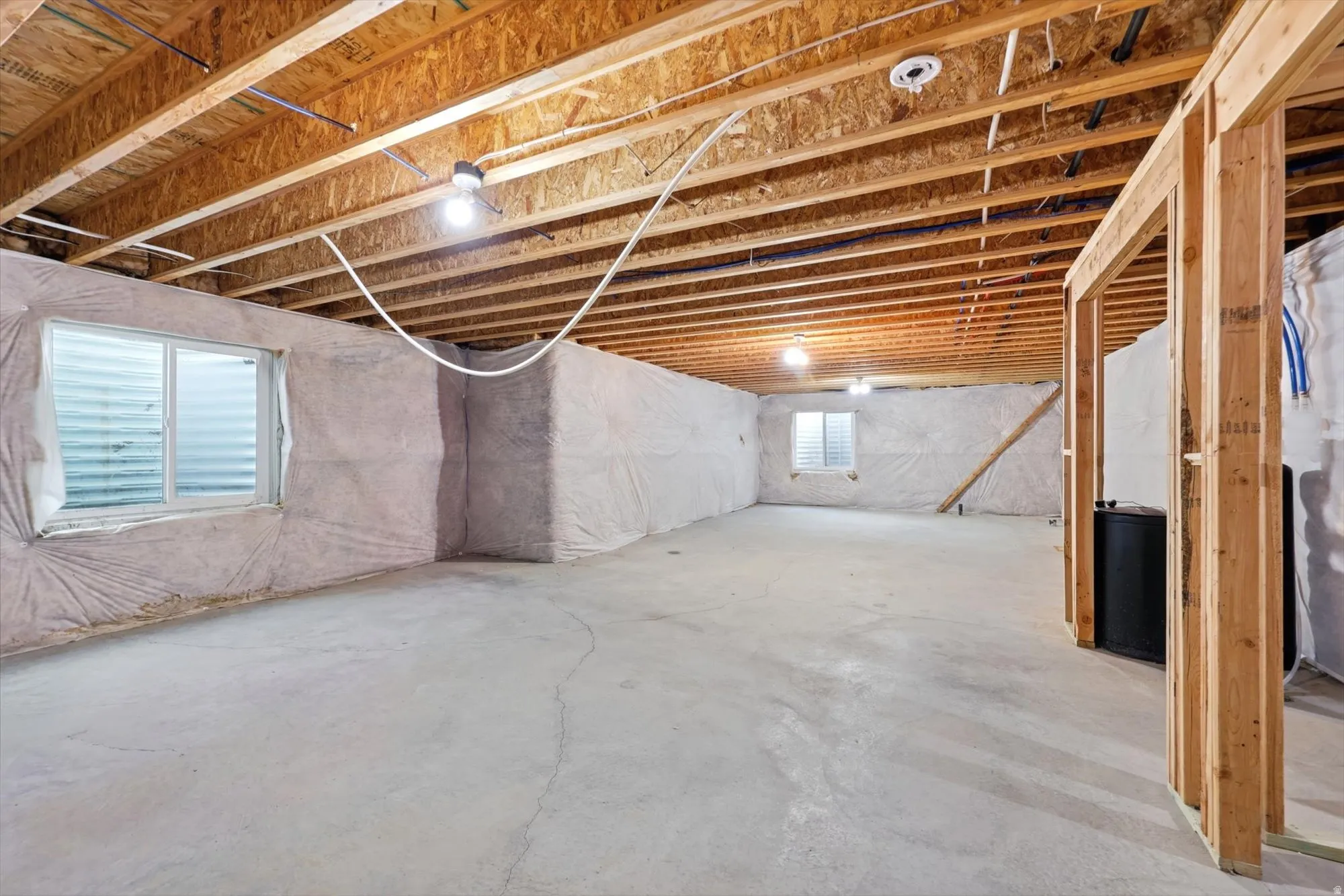 Unfinished basement space featuring exposed wood joists and concrete flooring