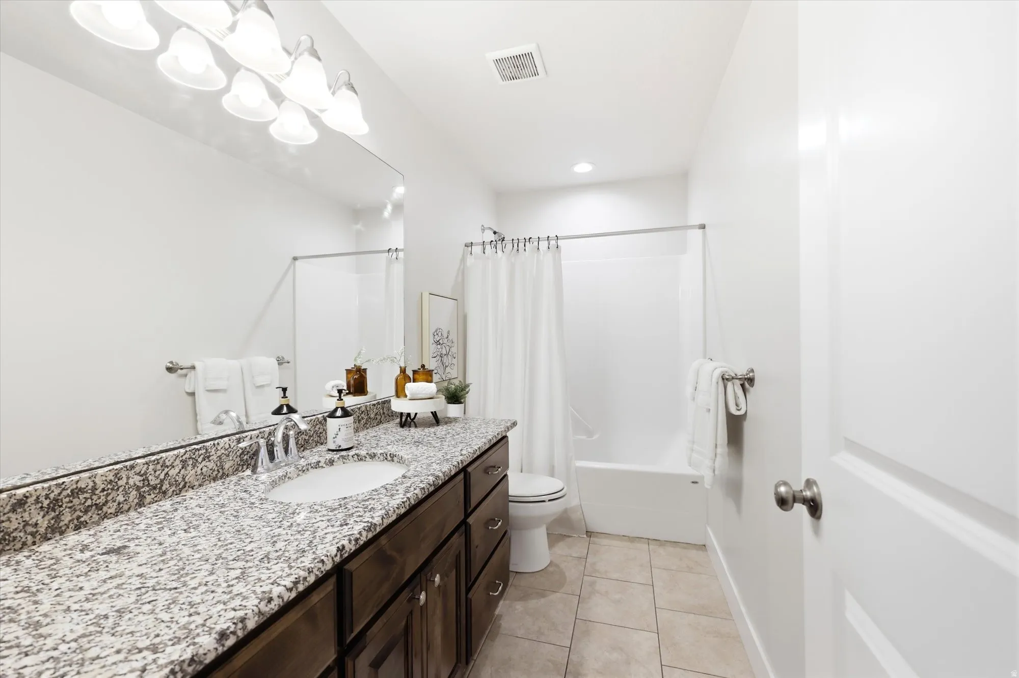 Bathroom featuring a wide vanity with a granite-style countertop, an undermount sink, and a chrome faucet