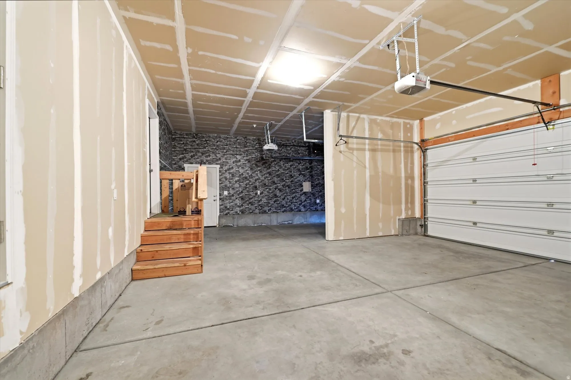 Spacious garage with exposed drywall, concrete flooring, and a sectional garage door