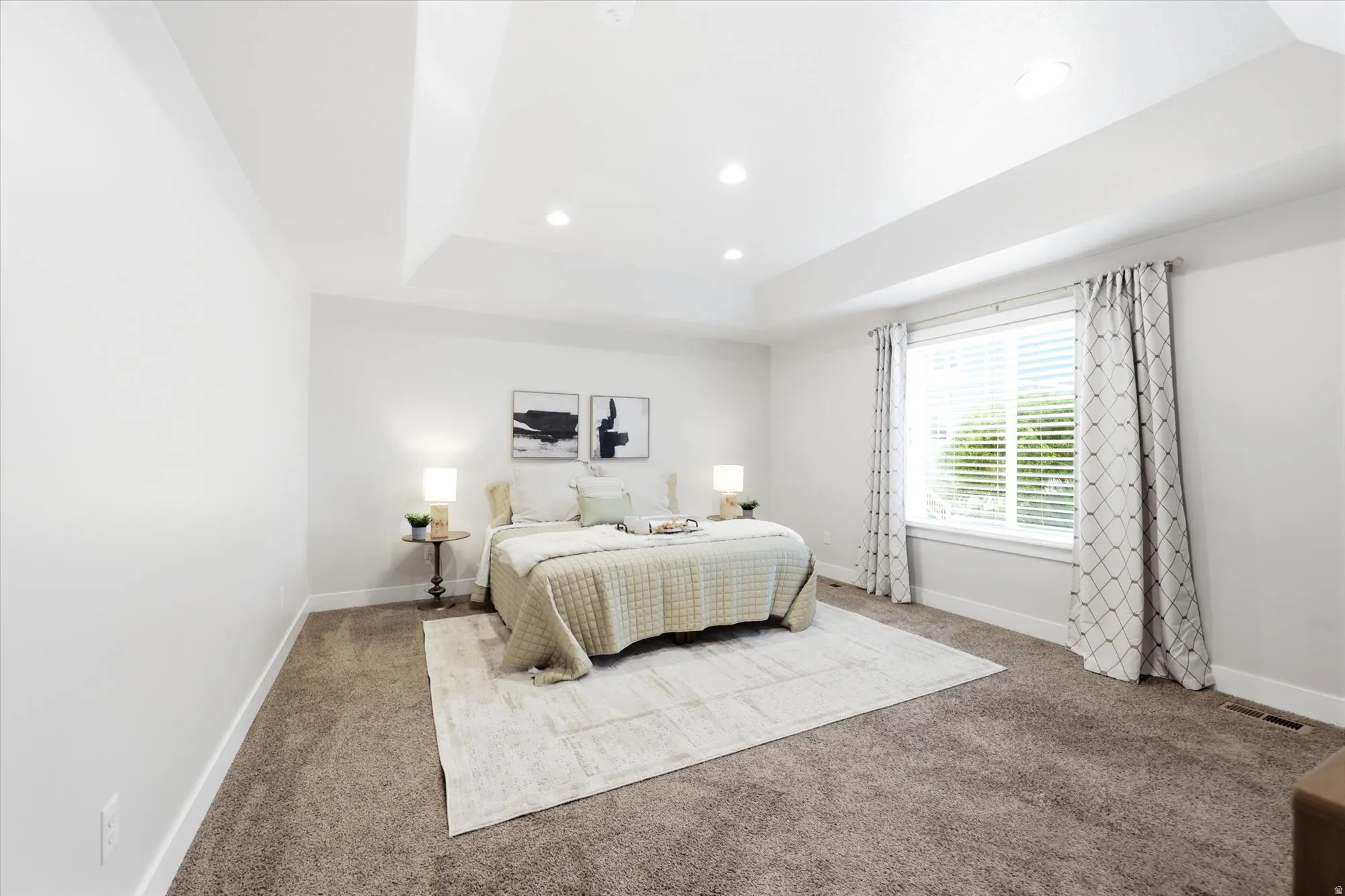 Recessed lighting highlights a tray ceiling in this carpeted room