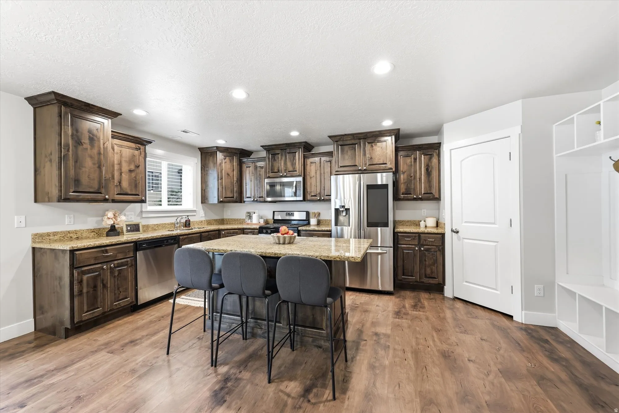 Kitchen featuring wood-finish flooring, dark wood cabinetry, and light-toned countertops