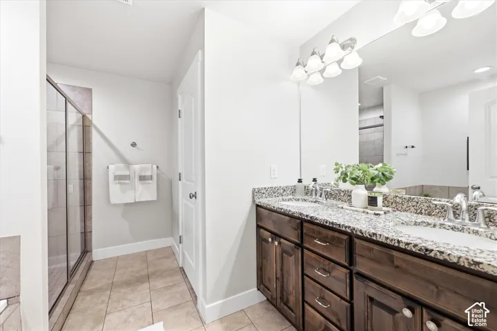 Dual vanity in master bedroom with dark wood cabinetry and granite countertops, featuring two undermount sinks and brushed nickel fixtures