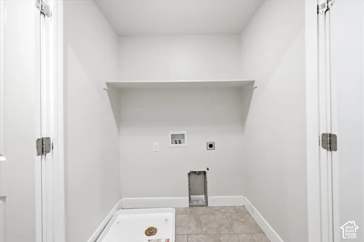 Dedicated utility space featuring a built-in shelf, plumbing hookups, and tiled flooring