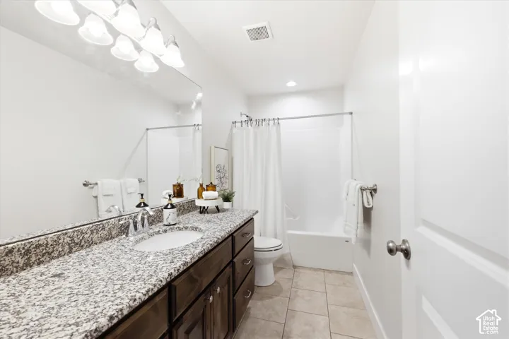 Bathroom featuring a wide vanity with a granite-style countertop, an undermount sink, and a chrome faucet