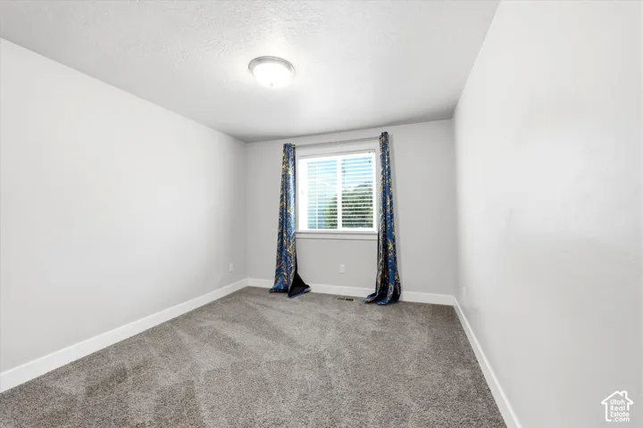 Carpeted room with a central window, white baseboards, light gray wall paint, and a ceiling-mounted light fixture