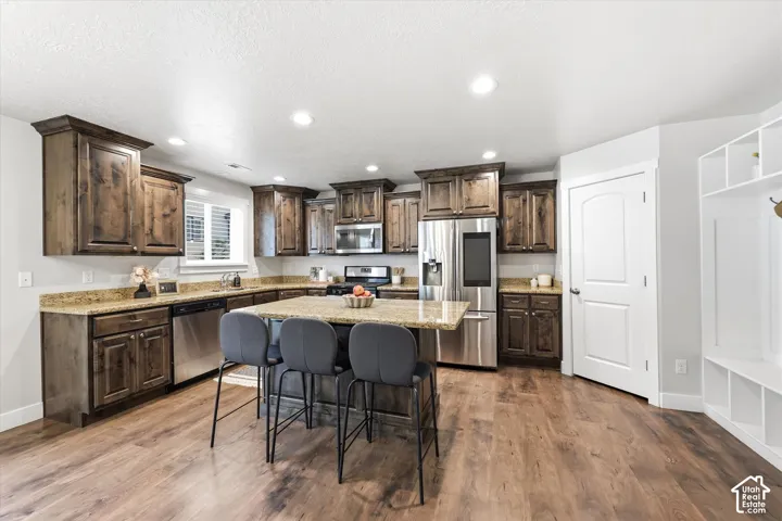 Kitchen featuring wood-finish flooring, dark wood cabinetry, and light-toned countertops